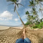 Hamak na plaży nad Bałtykiem, palmy i piaszczyste wybrzeże w tle, relaks w ośrodku